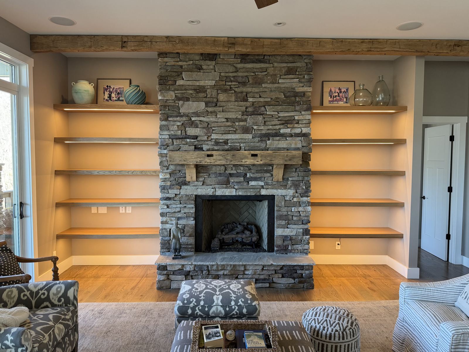 Lit custom built-in shelving flanking a fireplace in a finished living room